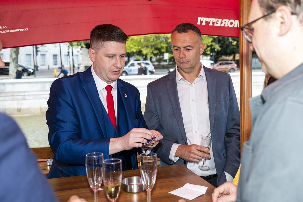 Pete James performing a card trick at the bar during a Thames boat party